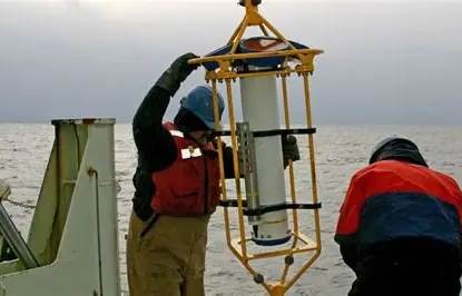 Survey crew deploying an ADCP from a vessel.