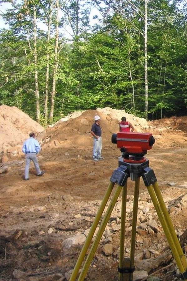 Automatic level set up on a tripod on an earthworks site.