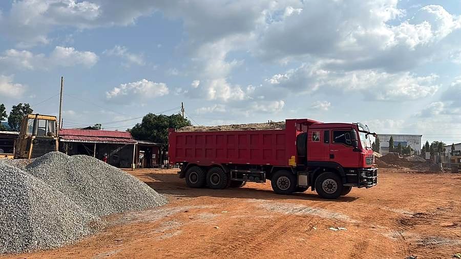 Red tipper truck and a gravel stockpile at a yard.